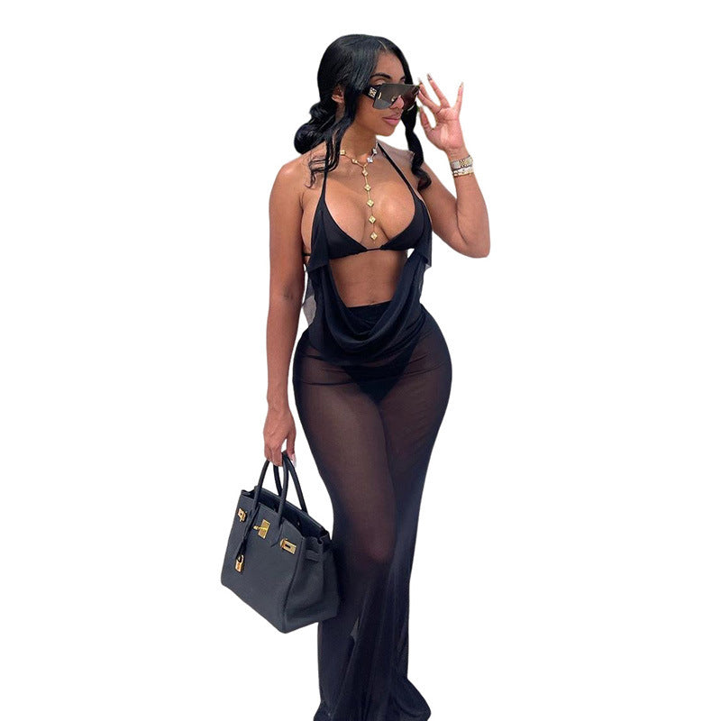 Woman wearing a black outfit with sheer elements, holding a black handbag on a white background