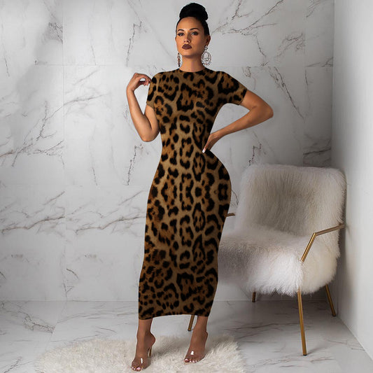 Woman wearing a leopard print dress in a room with a marble wall and white chair.