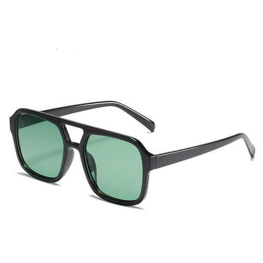 A person wearing square double beam retro sunglasses with a leopard print design on the frame, sitting in a vehicle.