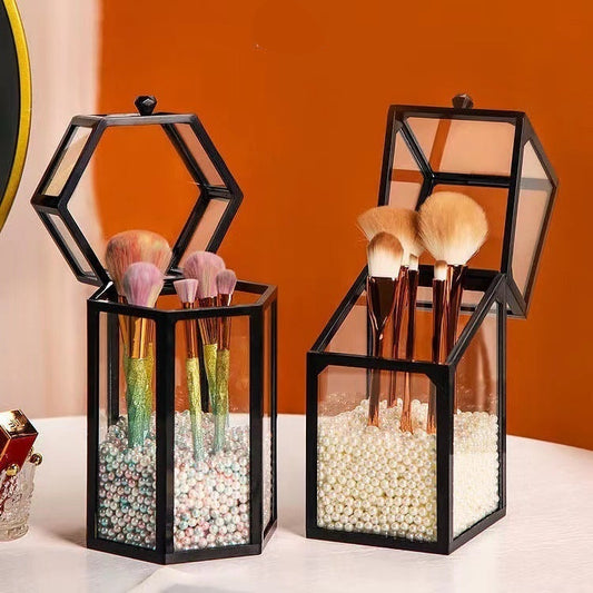 Two black geometric brush holders with makeup brushes on a table.