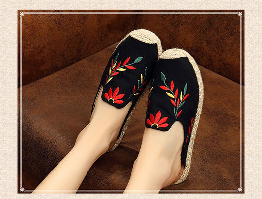 Black slippers with floral embroidery on a brown surface