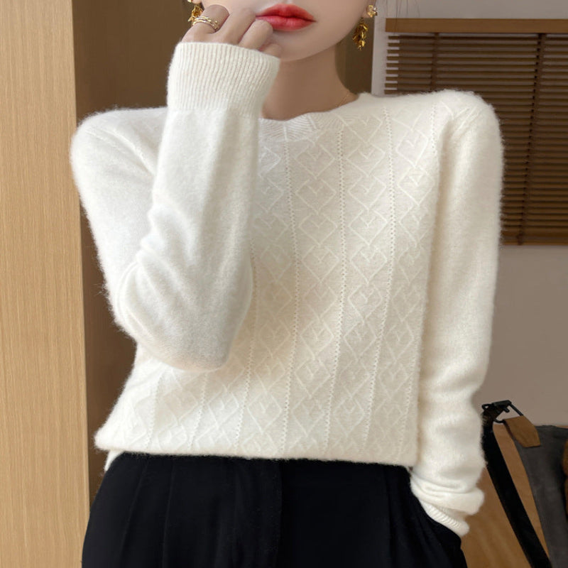 White cable knit sweater worn by a person with a blurred background