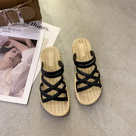 Pair of sandals with black straps on a gray surface next to a magazine.