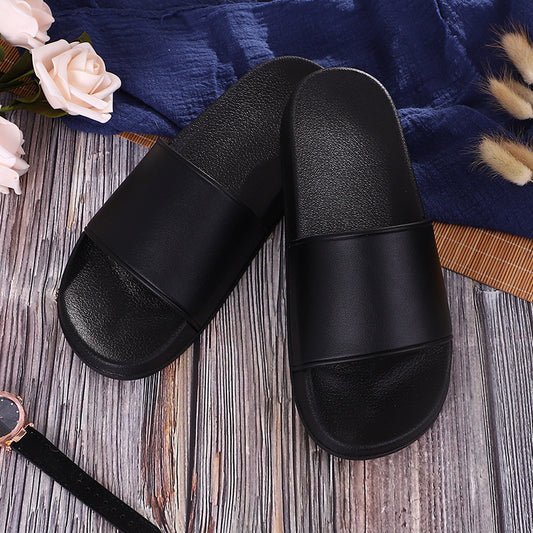 Black slippers on a wooden surface with flowers and a blue fabric background