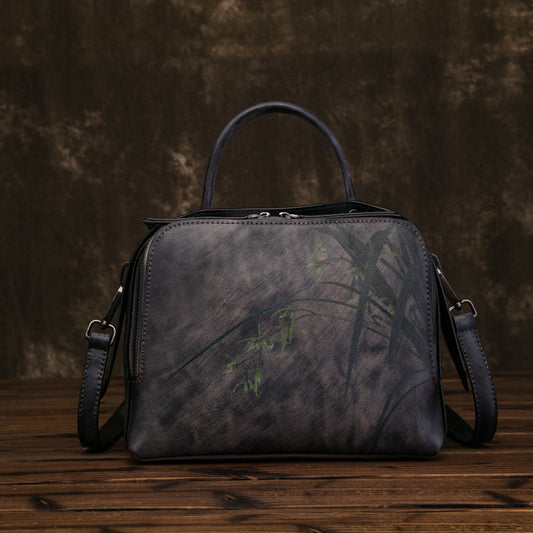 Dark brown leather handbag with floral pattern on a wooden surface and dark background