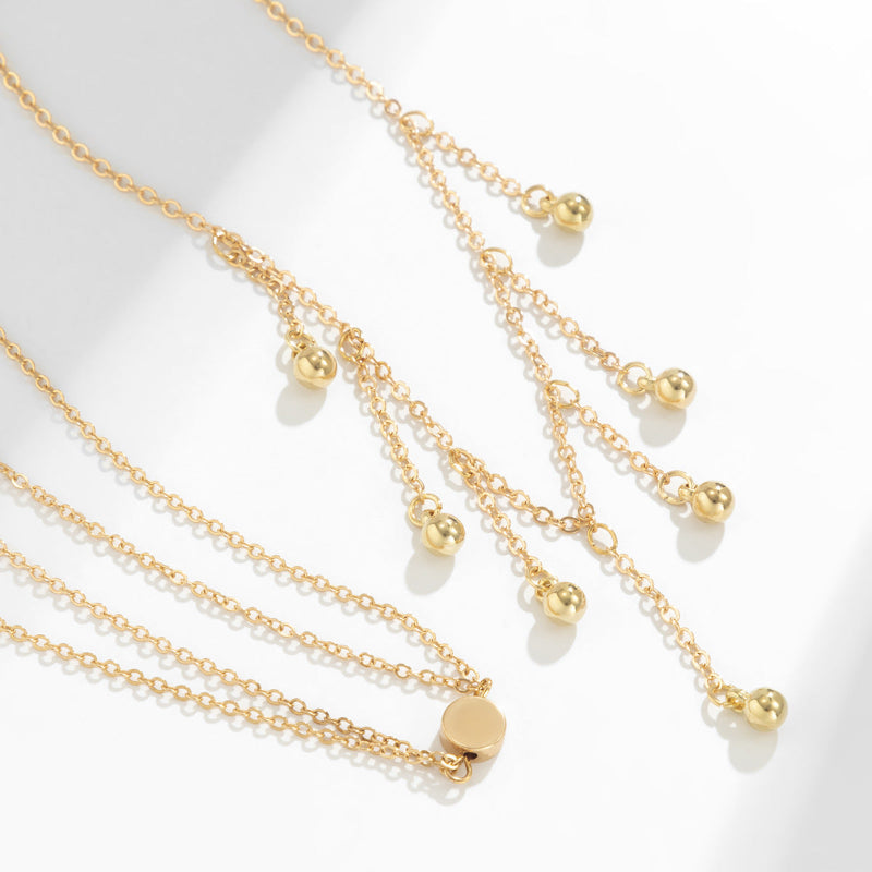 Gold necklaces with spherical pendants on a white background