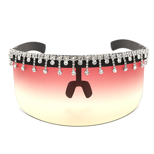 Sunglasses with a reflective pink and yellow lens and decorative black frame with crystals on a white background.