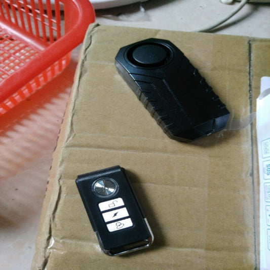 Black electronic device on a cardboard surface with a red basket in the background