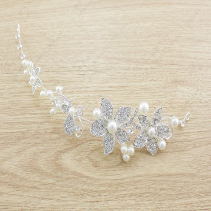A bridal jewelry set including a necklace, earrings, and a headpiece, featuring white pearls and silver-colored metal with a floral design.