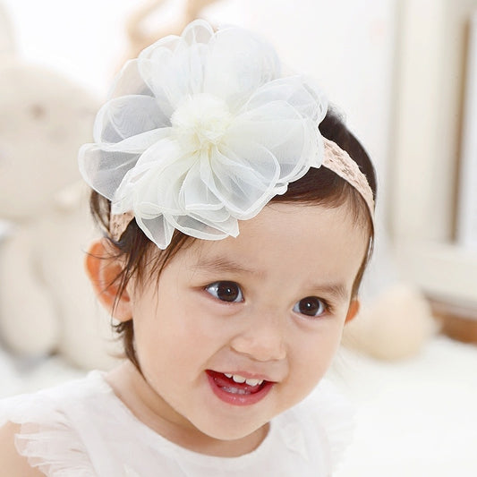 Baby wearing a white floral headband with a blurred background