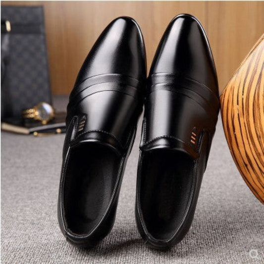 Pair of black dress shoes on a textured surface with a wooden object and black bag in the background.