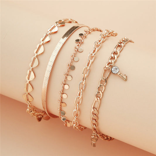 Set of rose gold bracelets on a beige surface