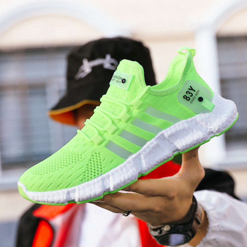 Neon green athletic shoe with white sole held by a person outdoors.