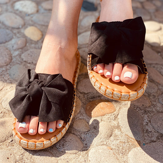 Black sandals with bows on a stone pavement