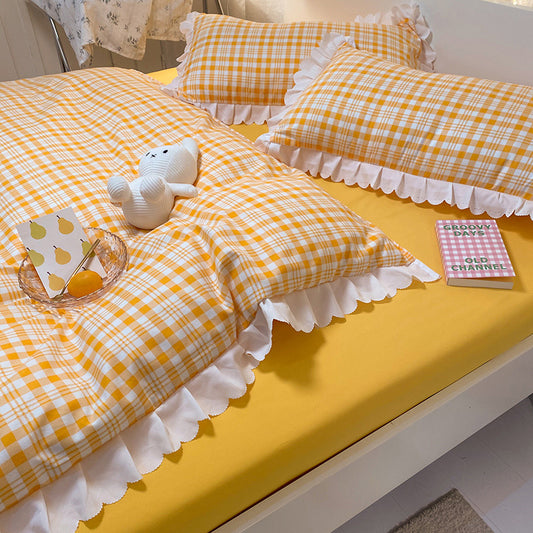 A bedding set with a yellow and white checkered pattern, including a duvet cover, bedsheet, and pillowcases, adorned with lace trim.
