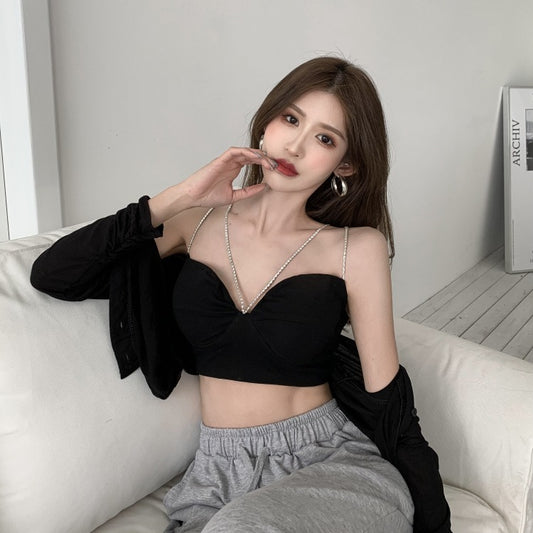 Woman wearing a black top and gray pants sitting on a white couch.