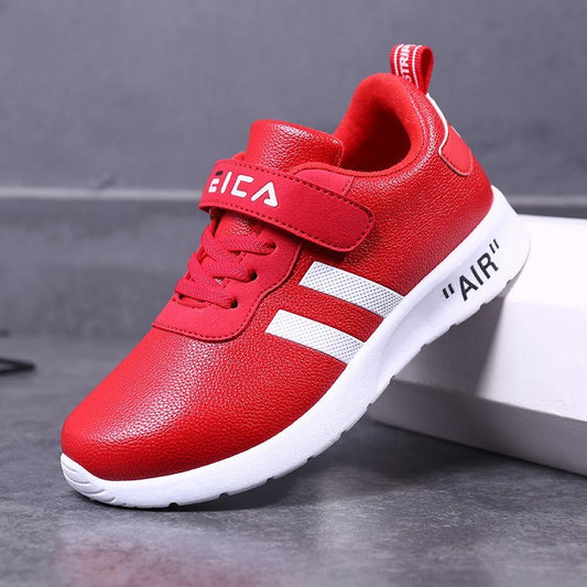 Red children's sneaker with white stripes on a gray background