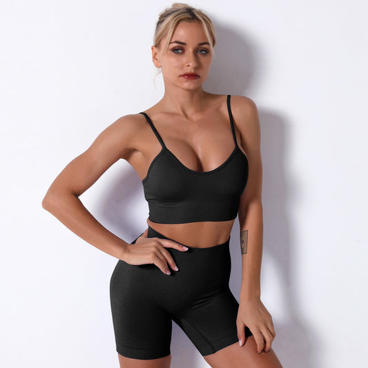 Woman wearing a black sports bra and shorts against a white background