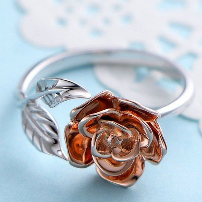 Rose gold and silver ring with rose design on a light blue background