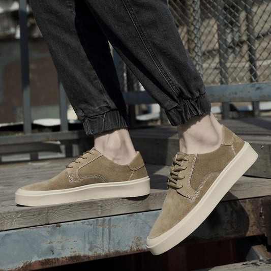 Beige sneakers worn with black pants on a wooden surface