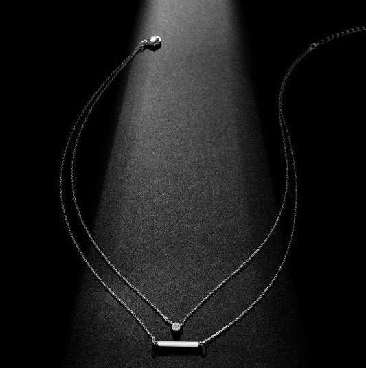 Silver necklace with small pendants on a black background