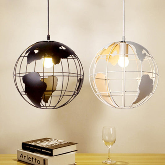 Two globe-shaped pendant lights on a table with books and a glass.