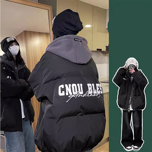 Person wearing a black jacket with text, standing indoors.