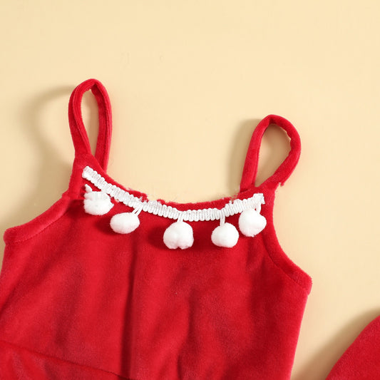 Red children's dress with white pom-pom trim on a beige background