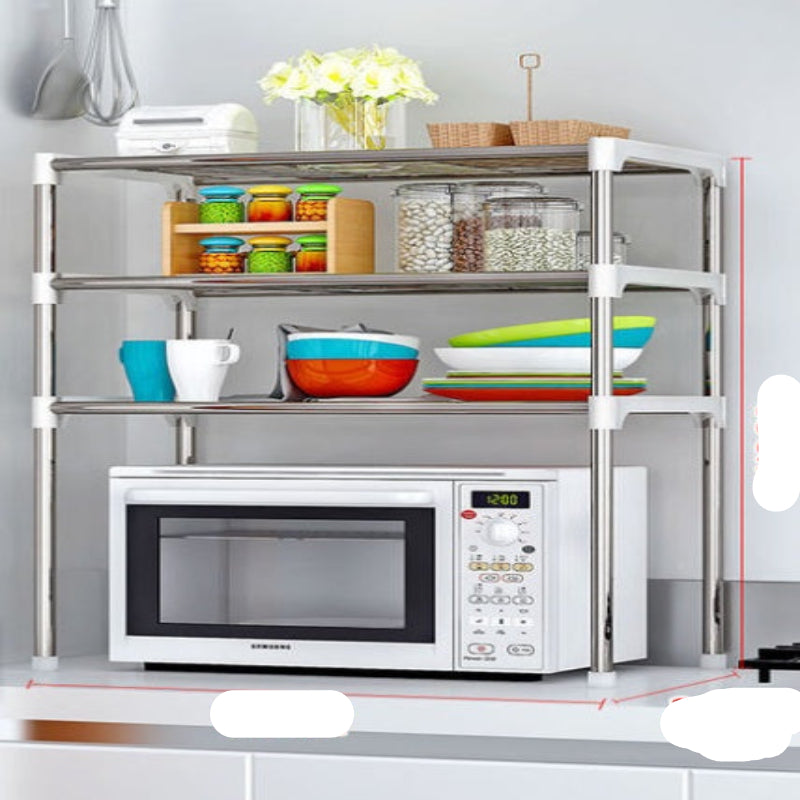 A silver and white microwave shelf rack with two tiers, placed over a microwave oven, storing various kitchen items like jars and containers on the upper shelf.