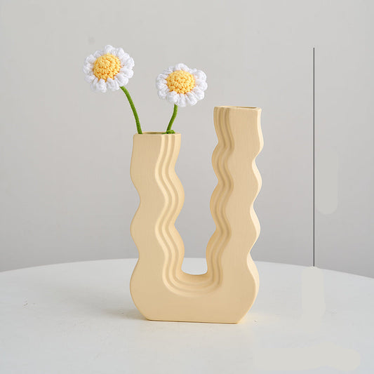 Wavy beige vase with two white flowers on a light gray background