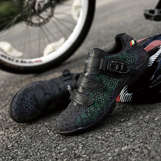Black cycling shoes with green pattern on a road next to a bicycle wheel
