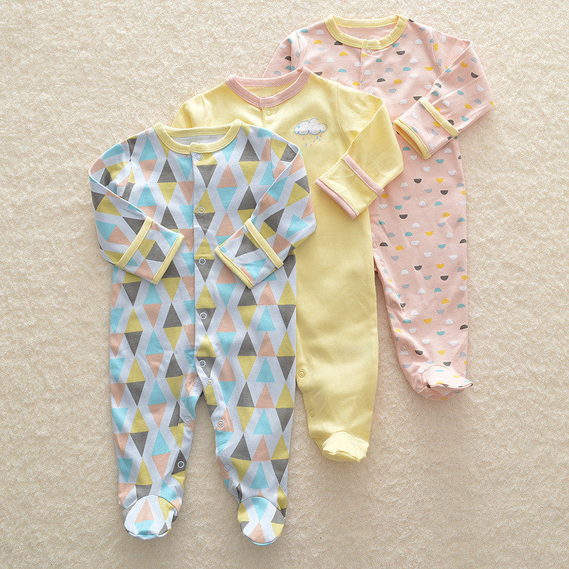 Three baby onesies with different patterns on a beige surface