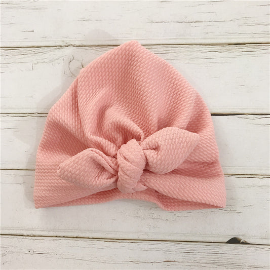 Pink knotted headband on a light wooden surface