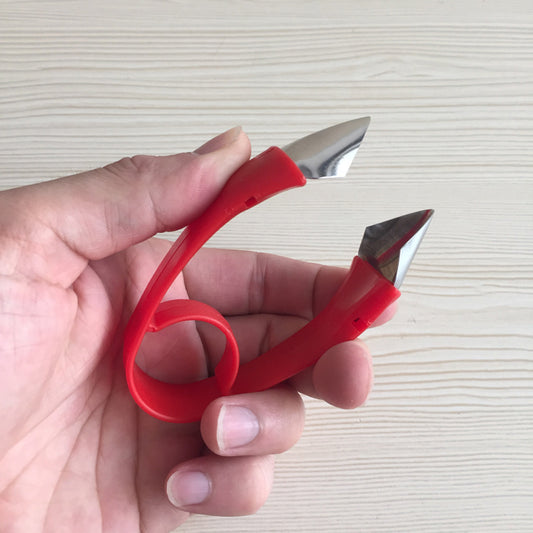 Hand holding a red nail clipper against a light background