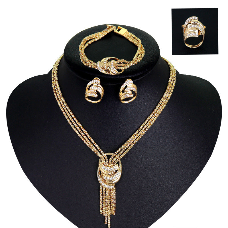 Gold jewelry set on a black stand with a close-up of a ring in the corner.
