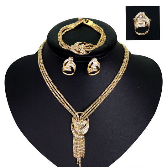 Gold jewelry set on a black stand with a close-up of a ring in the corner.