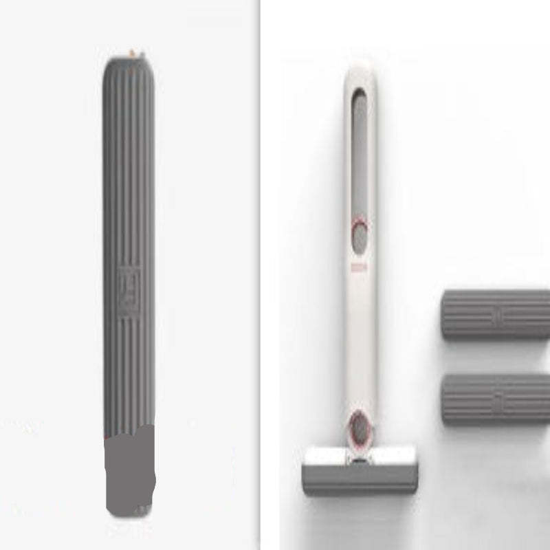 A white mini mop with a gray tip being held in a person's hand, demonstrating its use on a grey surface with water droplets indicating its cleaning capability.