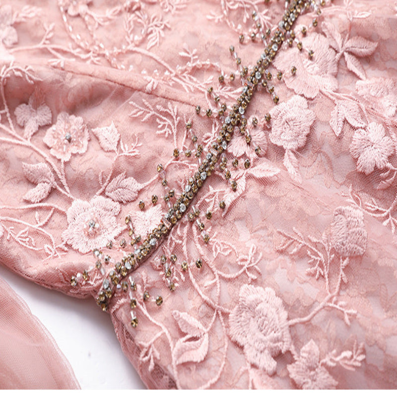 Close-up of pink embroidered fabric with floral patterns and bead details.