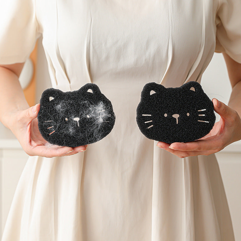 Two black cat-shaped sponges held by a person against a neutral background