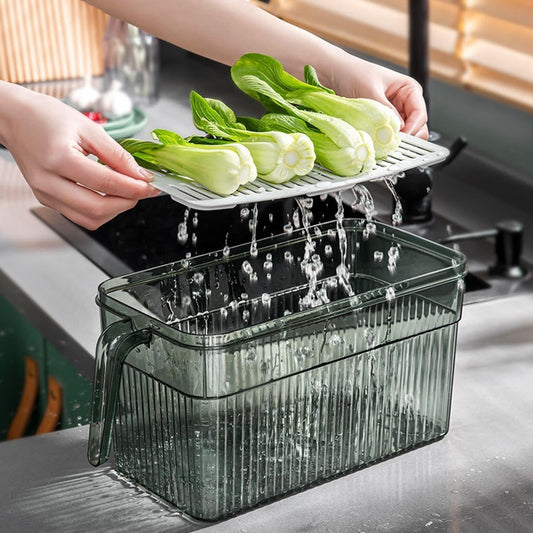 Person washing green vegetables under a running faucet with a transparent container below.
