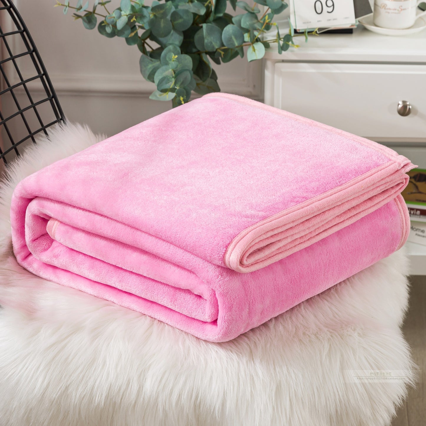 Pink blanket folded on a fluffy white surface.