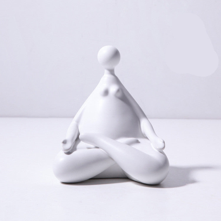 A pair of white ceramic figurines, one sitting and one standing, placed on top of a stack of books with a decorative vase beside them.