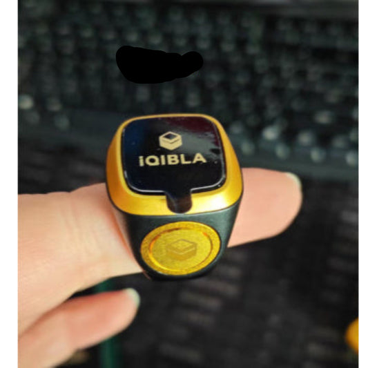 Gold and black device with 'IQIBLA' branding held by a hand on a blurred background