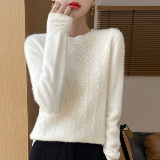 Person wearing a white cable knit sweater with a blurred background