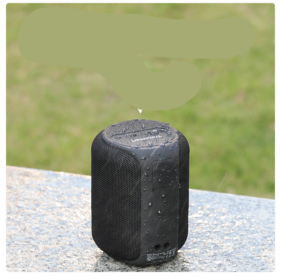 Black water-resistant speaker on a textured surface with grass background