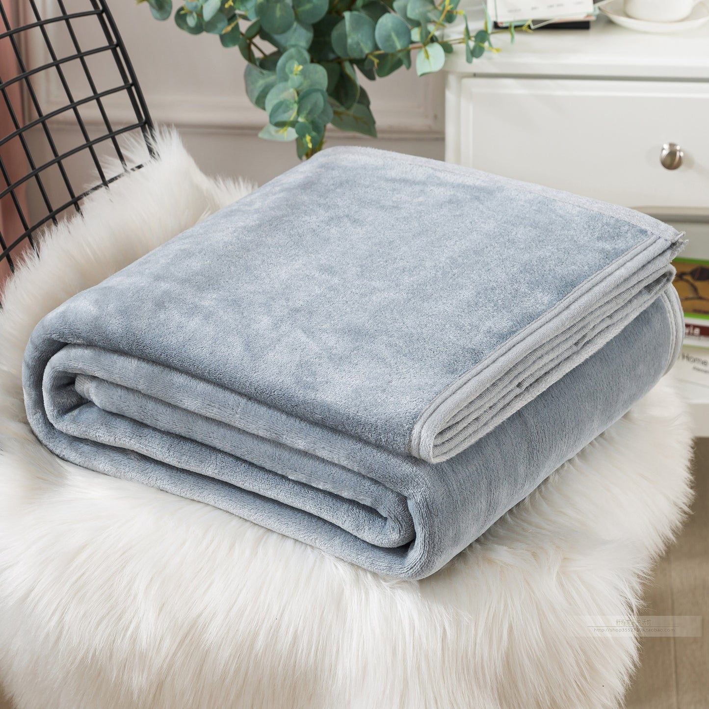 Folded light blue blanket on a fluffy white surface.