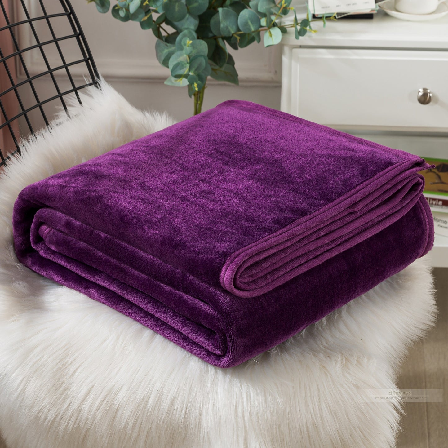 Folded purple blanket on a white fur surface.