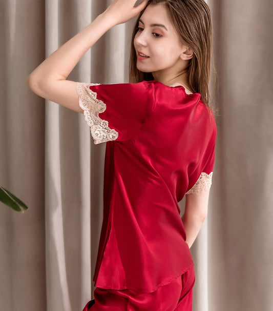 Woman wearing a red satin pajama set with lace trim against a neutral background