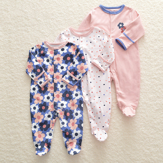 Three baby onesies with floral, polka dot, and solid designs on a beige surface.