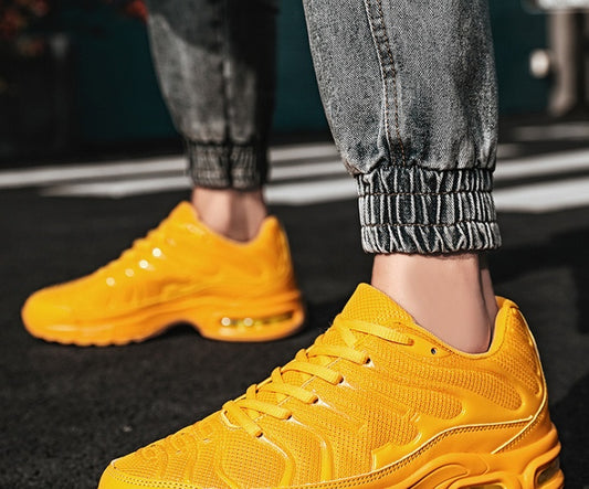 Yellow sneakers worn with gray pants on a blurred background